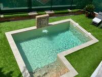 Piscina con cascada y césped artificial