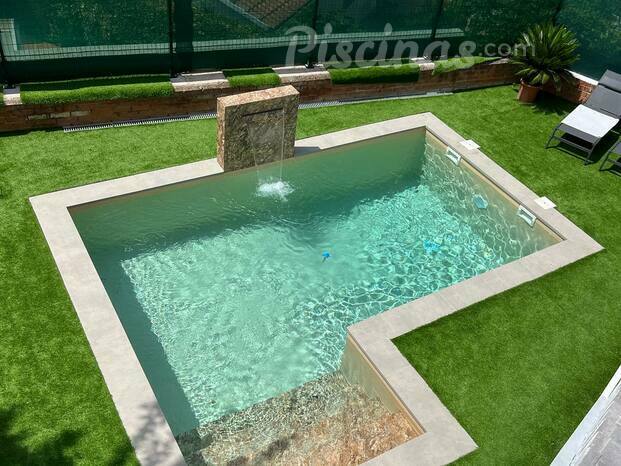 Piscina con cascada y césped artificial