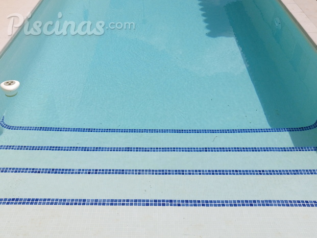 Piscina de gresite blanco y tiras azules en la escalera 