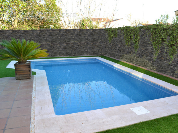 Piscina rectangular con escalera exterior y banco.