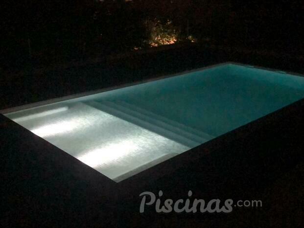 Piscina con playa iluminada. Imagen nocturna.